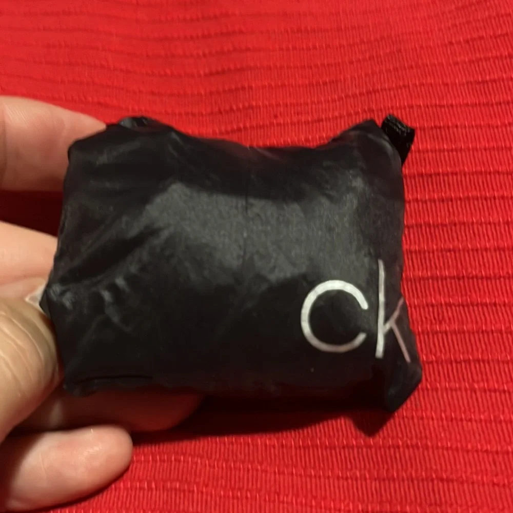 CK black draw string bag, used but great condition. Black and silver 12” x 5”